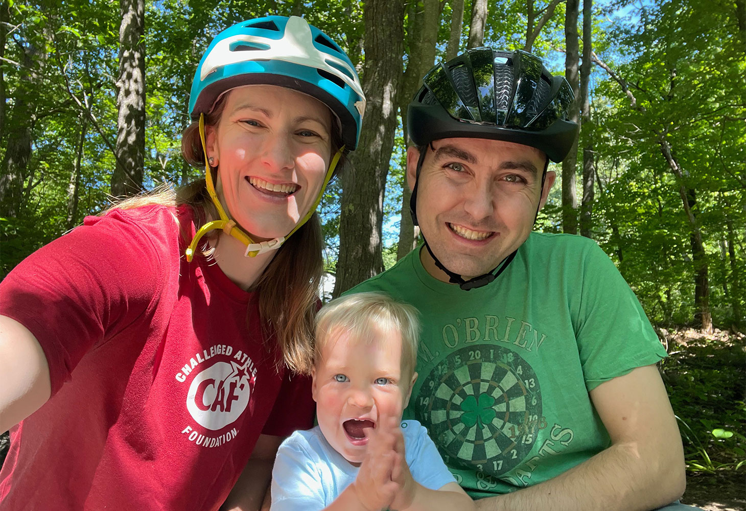 Meredith and her husband in bicycle helmets, with their two-year-old son.