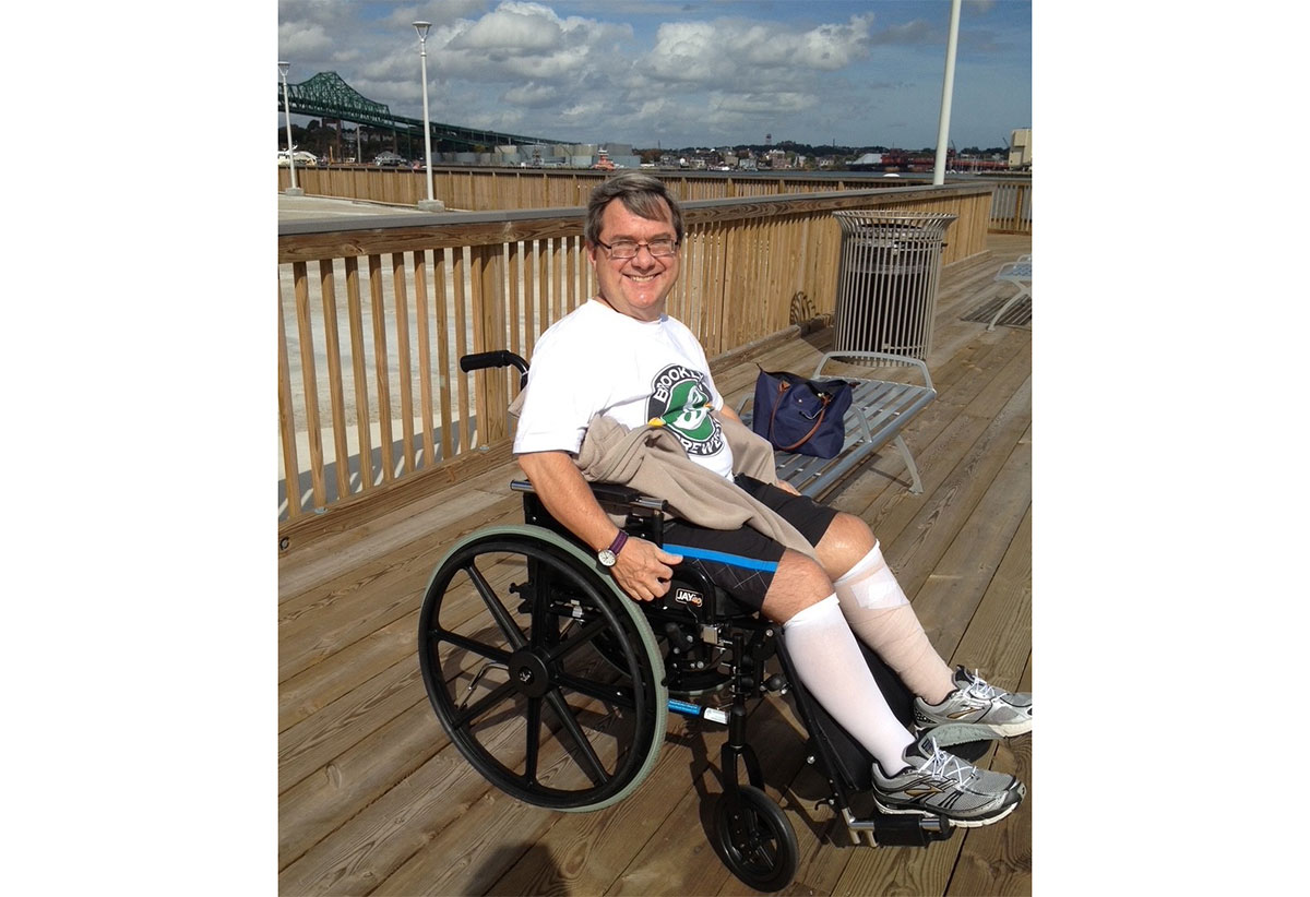 Michael, a middle-aged white man, in a wheelchair on a boardwalk at the beach.