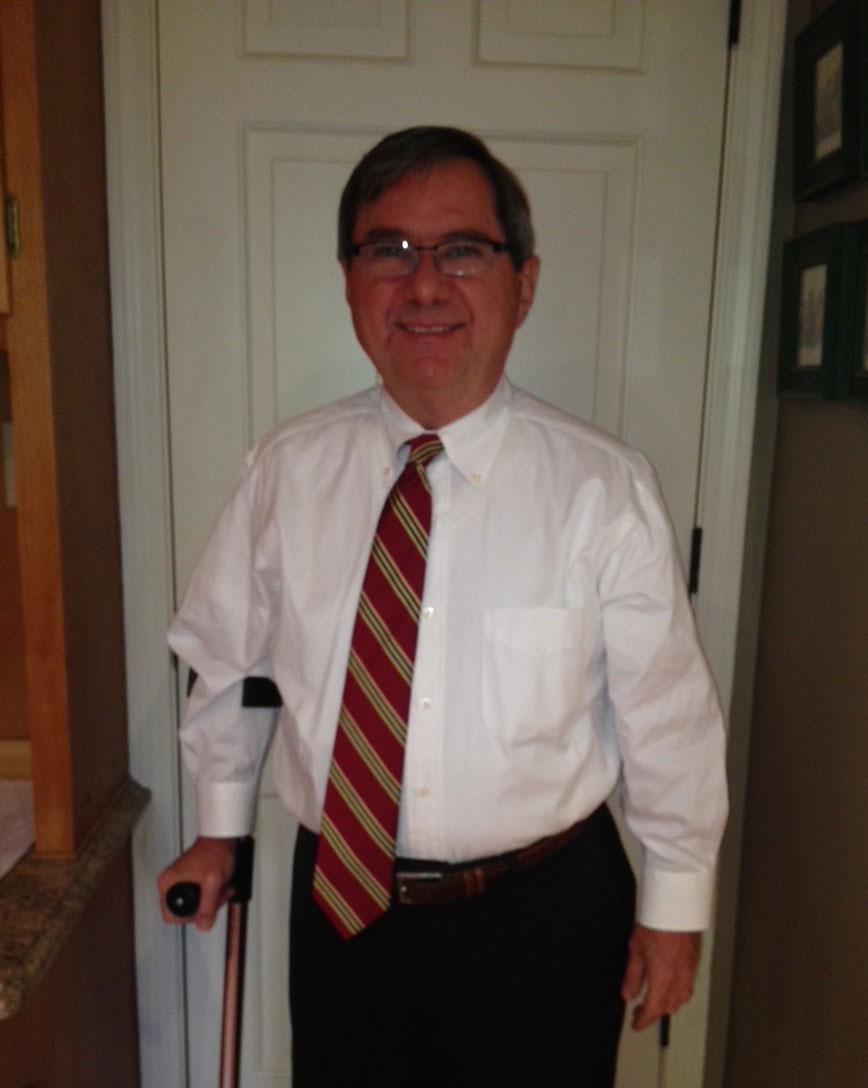 Michael standing in a hallway of his home with the help of a cane.